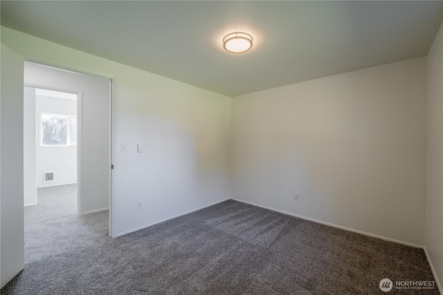 unfurnished room with visible vents, dark carpet, and baseboards