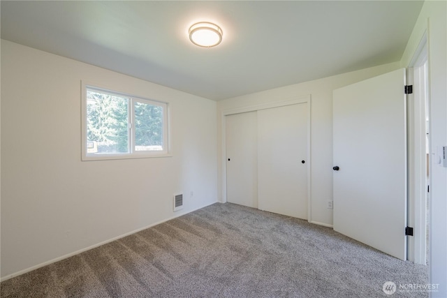 unfurnished bedroom with light colored carpet, a closet, and visible vents