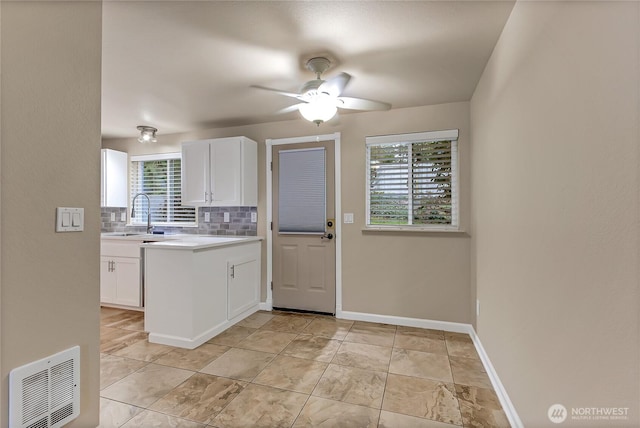 kitchen with white cabinets, light countertops, visible vents, and decorative backsplash