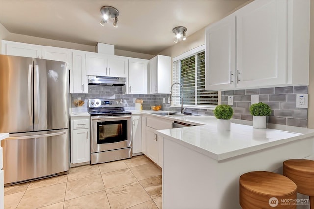 kitchen featuring under cabinet range hood, white cabinetry, appliances with stainless steel finishes, and a sink