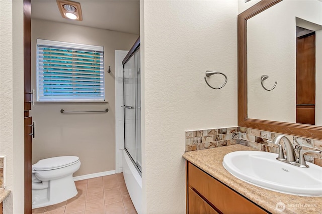 bathroom with tile patterned flooring, toilet, vanity, baseboards, and combined bath / shower with glass door