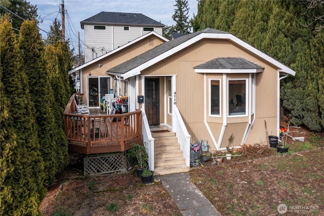 view of front of house with a deck and roof with shingles