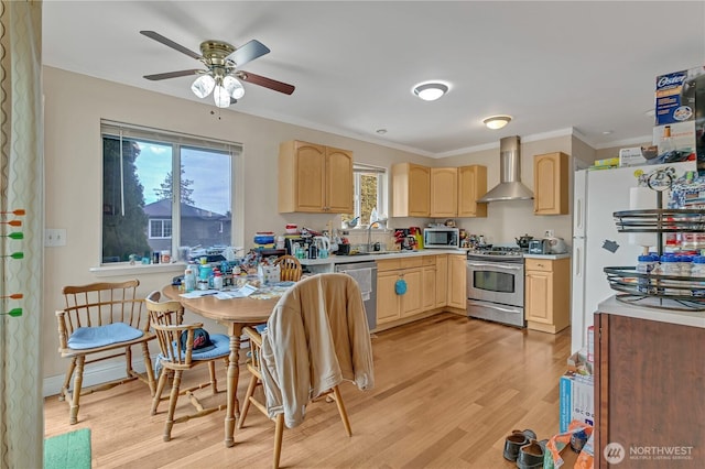 kitchen with light brown cabinets, stainless steel appliances, a sink, light countertops, and wall chimney exhaust hood