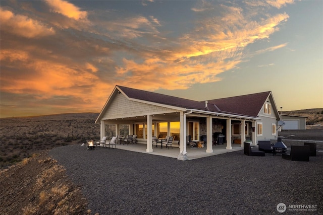 back of house at dusk featuring a patio area