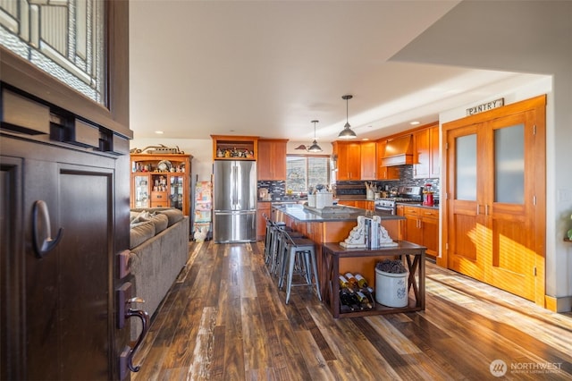 kitchen with appliances with stainless steel finishes, dark wood-type flooring, dark countertops, and a center island