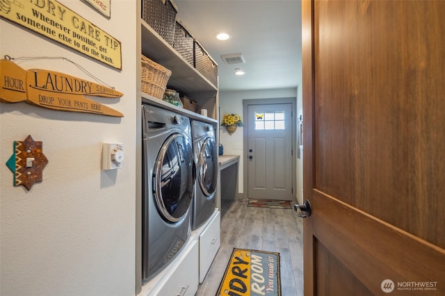 laundry area with laundry area, washing machine and dryer, visible vents, and light wood-style flooring