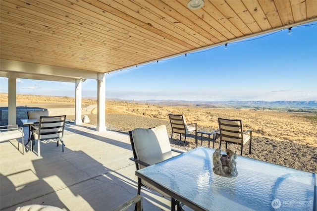 view of patio / terrace featuring a desert view, a mountain view, and outdoor dining area