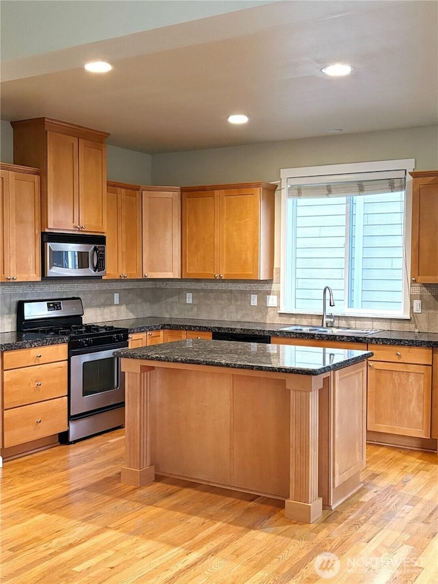 kitchen with tasteful backsplash, light wood-style flooring, a center island, stainless steel appliances, and a sink