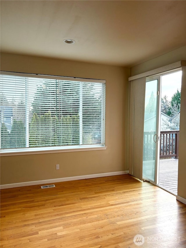 spare room with light wood-style floors, baseboards, and visible vents