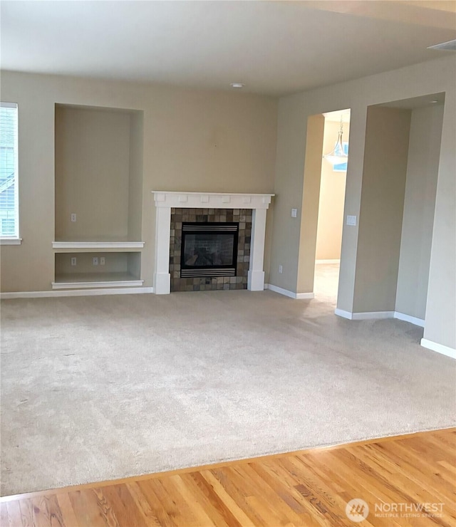 unfurnished living room featuring a fireplace, baseboards, and wood finished floors