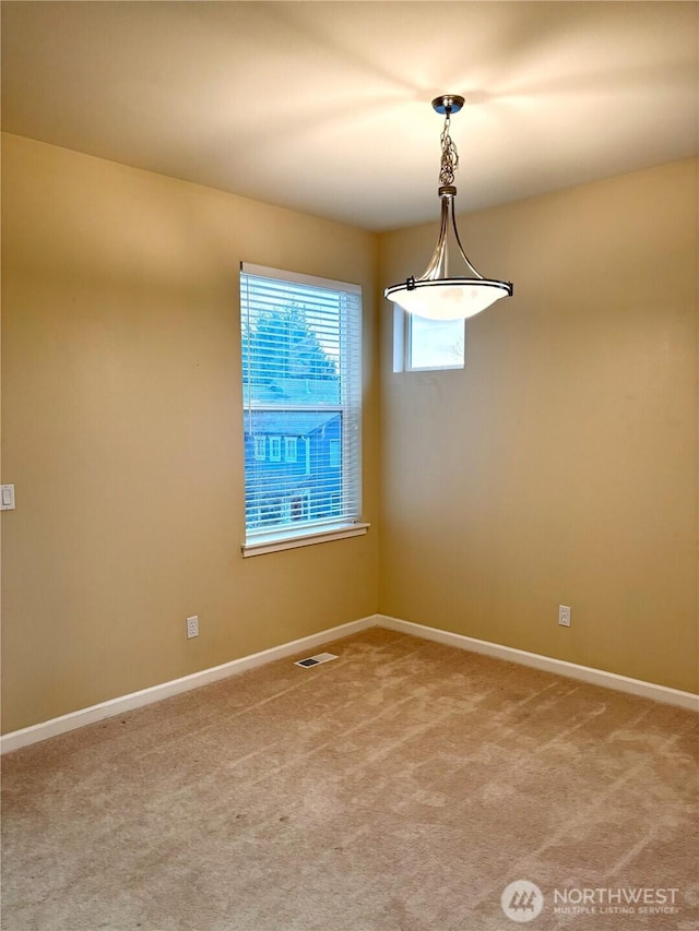 spare room featuring light colored carpet, visible vents, and baseboards