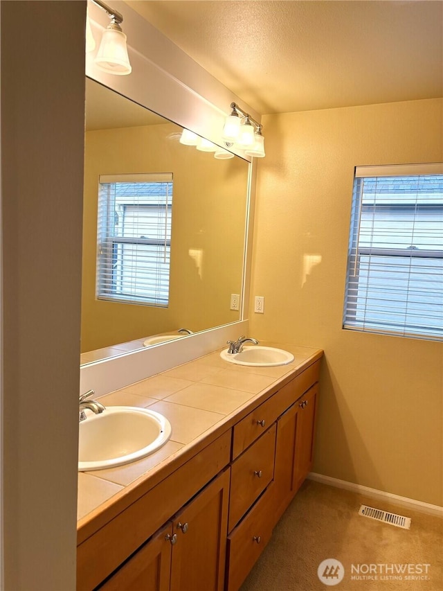 full bathroom featuring double vanity, visible vents, baseboards, and a sink