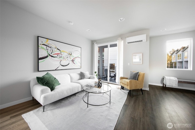 living area featuring a healthy amount of sunlight, baseboards, an AC wall unit, and wood finished floors