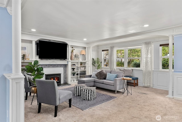 carpeted living room featuring recessed lighting, a brick fireplace, a decorative wall, and ornate columns