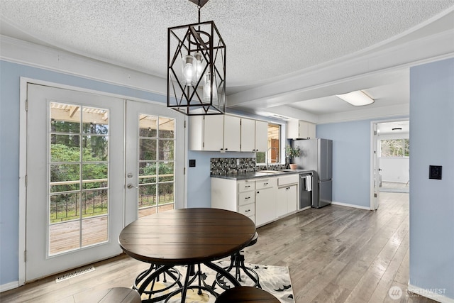 dining area featuring a textured ceiling, french doors, light wood-style flooring, and visible vents