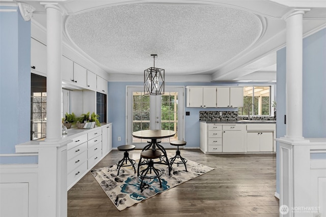 kitchen featuring ornate columns, plenty of natural light, white cabinetry, and a sink