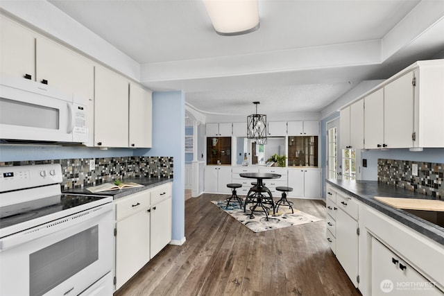 kitchen with white appliances, white cabinets, dark wood-style floors, tasteful backsplash, and dark countertops