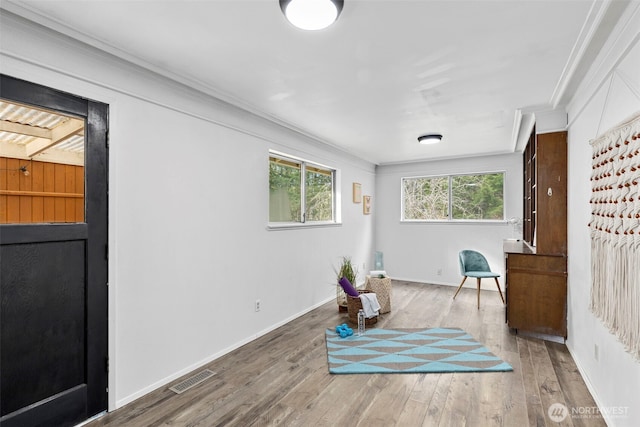 living area featuring ornamental molding, visible vents, baseboards, and wood finished floors