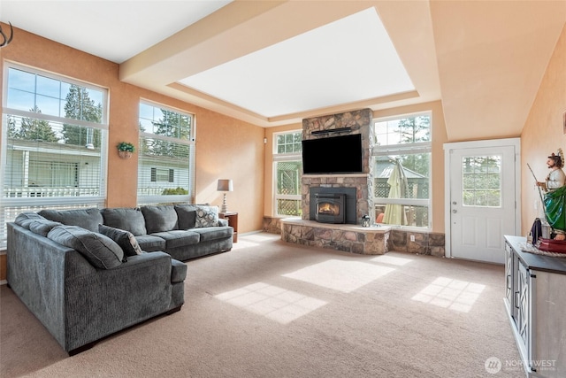 carpeted living area with a tray ceiling and a fireplace