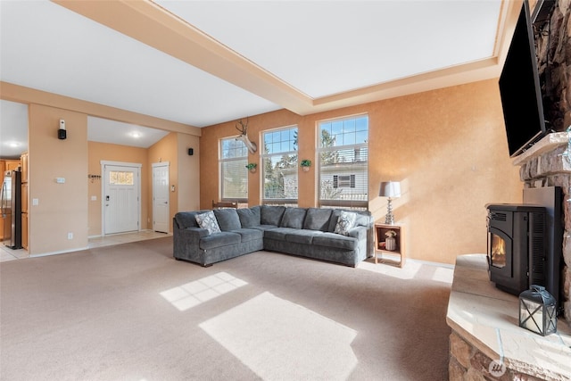 carpeted living room with a wood stove and baseboards