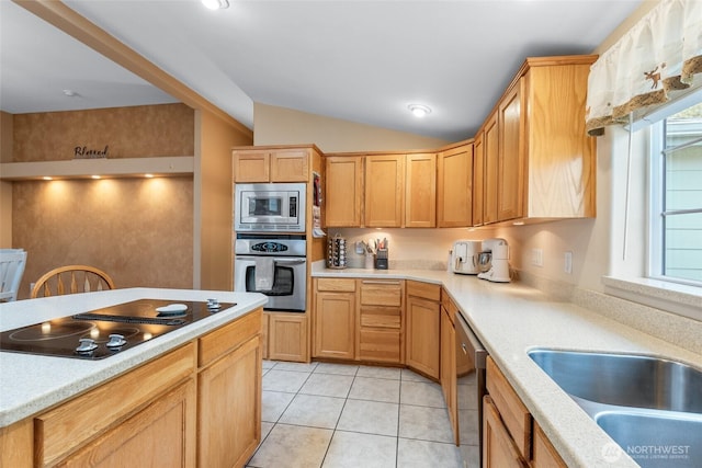 kitchen featuring lofted ceiling, light tile patterned flooring, stainless steel appliances, a sink, and light countertops