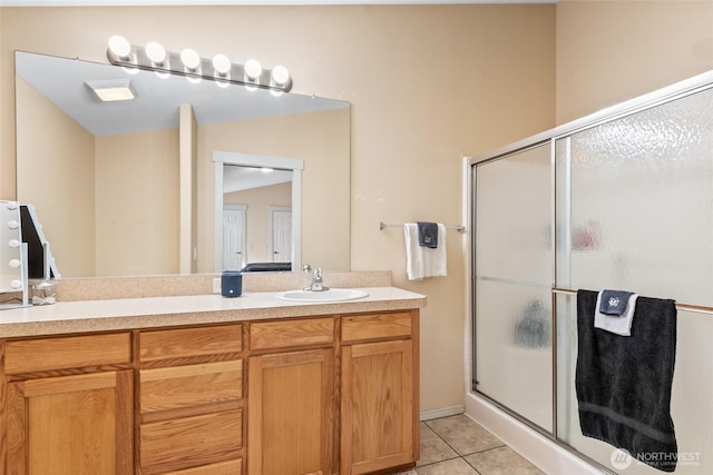 bathroom featuring double vanity, tile patterned flooring, a sink, and a shower stall