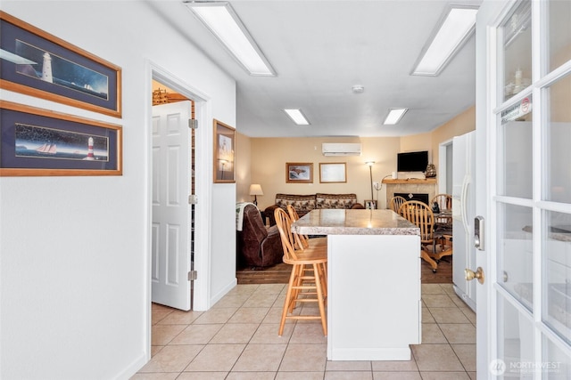 kitchen featuring light tile patterned floors, light countertops, a wall mounted AC, open floor plan, and a kitchen bar