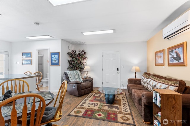 living room with an AC wall unit, baseboards, and wood finished floors