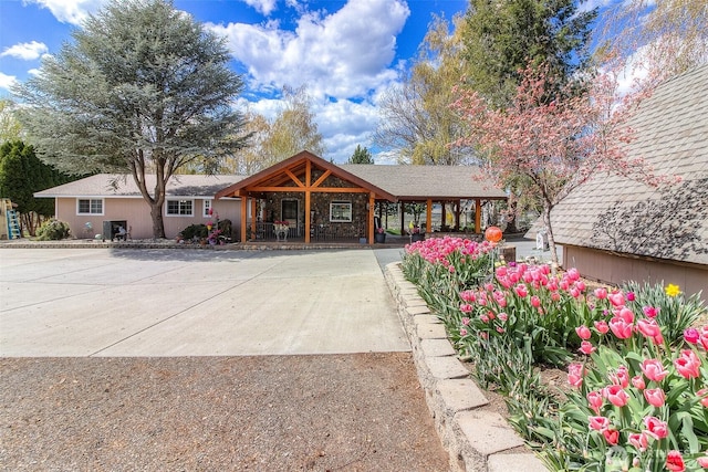 view of front of property with a carport, a porch, concrete driveway, and stucco siding