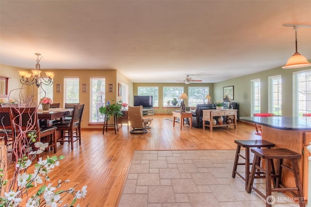 dining space with ceiling fan with notable chandelier and light wood-style floors