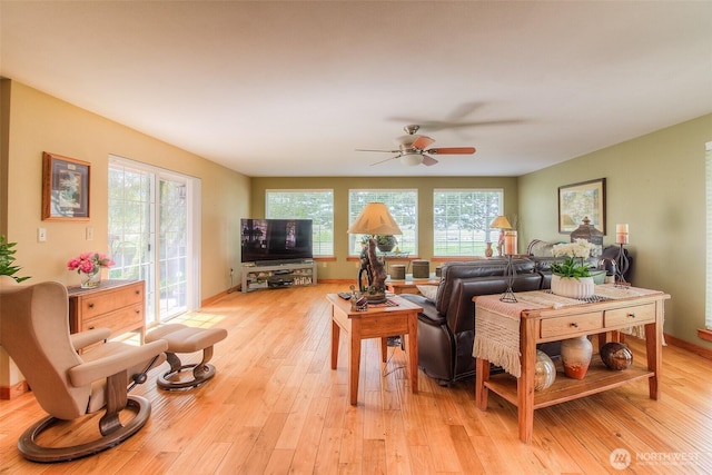 living area with baseboards, light wood-style flooring, and a ceiling fan