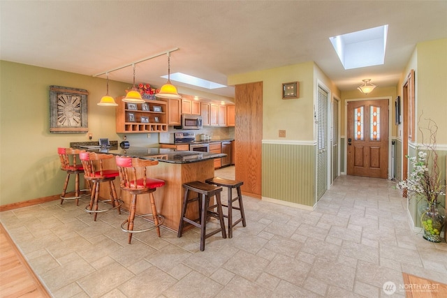 kitchen with open shelves, appliances with stainless steel finishes, a breakfast bar area, and wainscoting