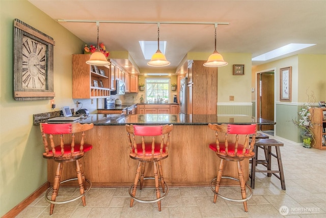 kitchen featuring open shelves, dark countertops, hanging light fixtures, appliances with stainless steel finishes, and a peninsula