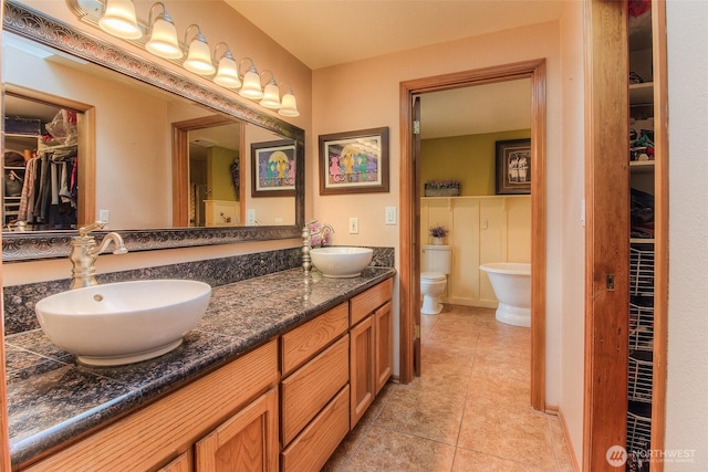 bathroom featuring a sink, a spacious closet, toilet, and double vanity