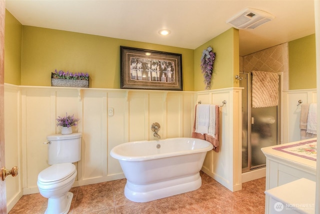 bathroom featuring visible vents, toilet, a shower stall, a freestanding tub, and tile patterned floors