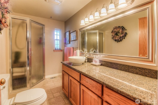 bathroom with a stall shower, visible vents, baseboards, stone tile flooring, and vanity