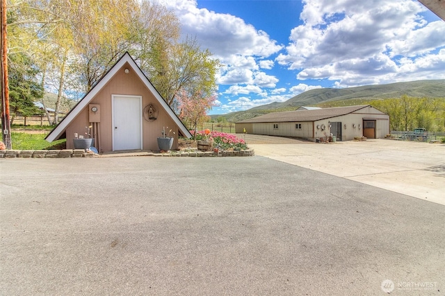 view of front of property with a mountain view, an outdoor structure, and fence