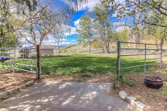 view of yard featuring an outbuilding, a gate, a rural view, and fence