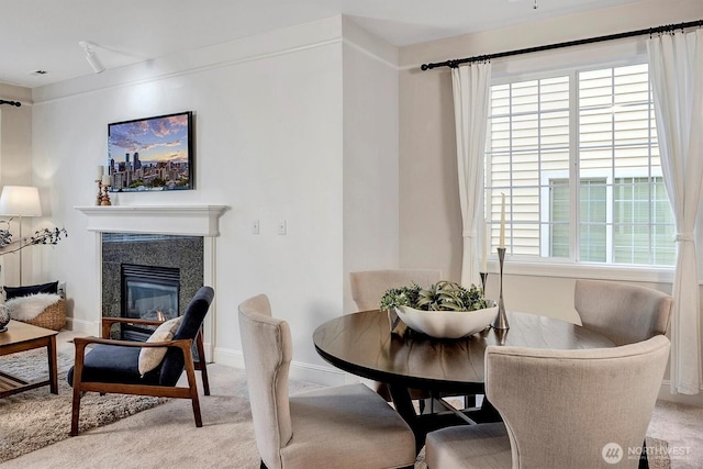 dining area featuring a fireplace, baseboards, and light carpet