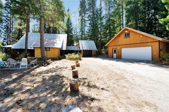 view of property exterior featuring an outbuilding, metal roof, and a detached garage