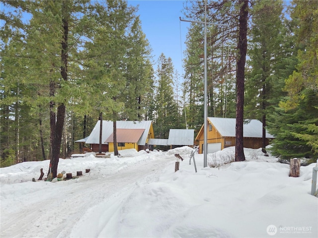 snowy yard with a garage and an outdoor structure