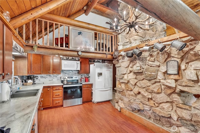 kitchen featuring brown cabinets, white appliances, light countertops, and a sink