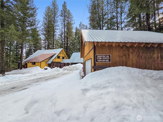 view of snow covered exterior featuring a garage and metal roof