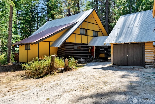 view of front of property with an outbuilding, metal roof, and log siding