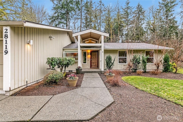 view of front facade featuring a shingled roof and crawl space