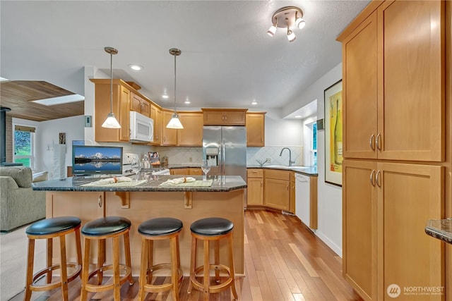 kitchen with light wood-style flooring, decorative backsplash, open floor plan, white appliances, and a peninsula