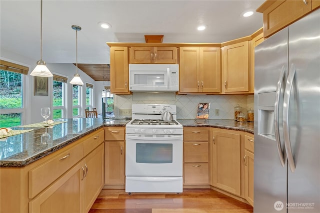 kitchen featuring light wood-style flooring, white appliances, a peninsula, and backsplash