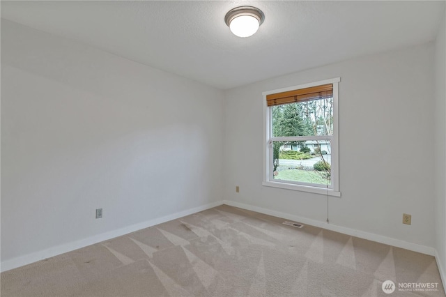 carpeted spare room with visible vents and baseboards