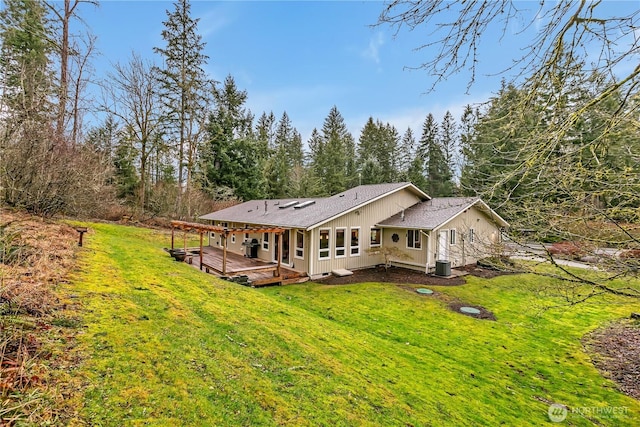 rear view of property featuring central air condition unit, a deck, and a yard