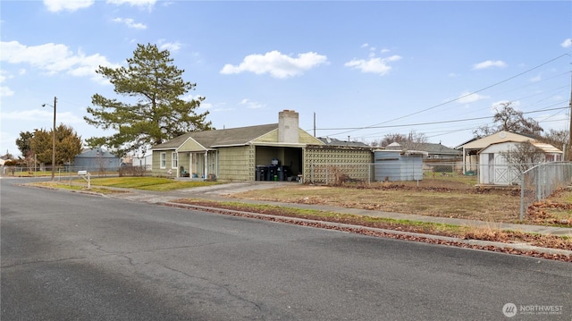 view of front facade featuring a chimney, fence, and concrete driveway